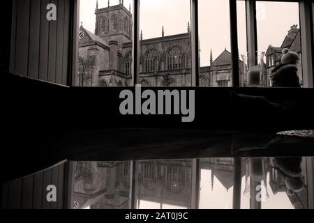 Sherborne Abbey durch Pub-Fenster, das sich in kupferbeschlagenen Tischen widerspiegelt Stockfoto