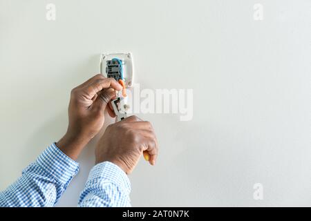 Afroamerikanischer Elektriker installiert Schalter im Raum Stockfoto