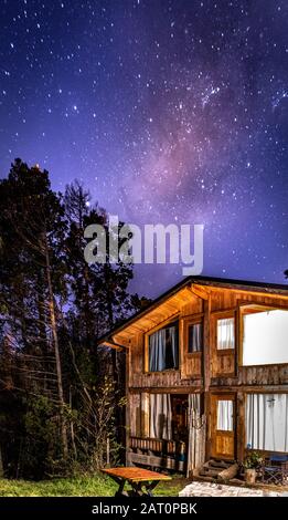 Bariloche, ARGENTINIEN, 19. JUNI 2019: Außenansicht einer gemütlichen und entspannenden Holzhütte im Wald mit einem wundervollen Sternenhimmel Stockfoto