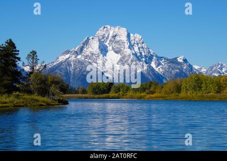 Der Grand Tetons's Mount Moran ragt majestätisch über den Schlangenfluss und die schönen Herbstfarben des Waldes. Stockfoto