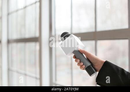 Weibliche Journalistin mit Mikrofon im Innenbereich Stockfoto
