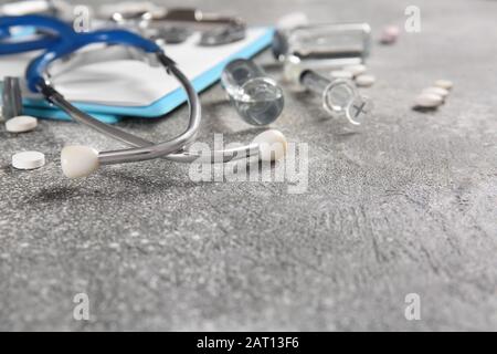 Stethoskop mit Medikamenten auf grauem Hintergrund Stockfoto