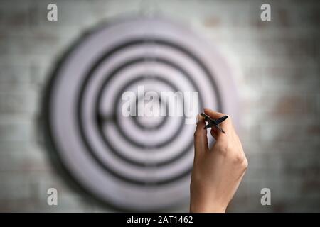 Junge Frau, die Darts in Innenräumen spielt Stockfoto