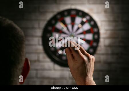 Junge Mann spielt Dart im Innenbereich Stockfoto