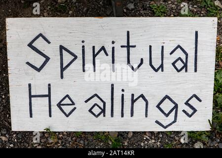 Handschriftlich unterzeichtes Schild, das auf einer Staffelei auf dem örtlichen Bauernmarkt ruht. Schild informiert über spirituelle Heilungspraxis. Schwarze Buchstaben auf weißem Hintergrund. Stockfoto