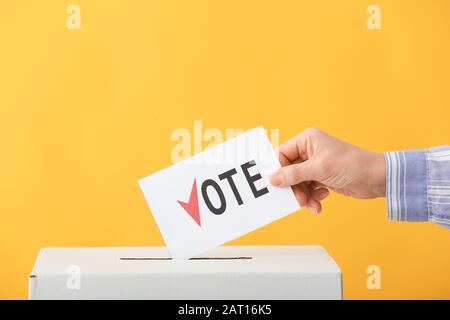 Wahlfrau in der Nähe der Wahlurne auf Farbhintergrund Stockfoto