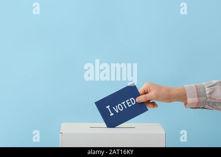 Wahlfrau in der Nähe der Wahlurne auf Farbhintergrund Stockfoto