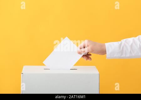 Wahlfrau in der Nähe der Wahlurne auf Farbhintergrund Stockfoto