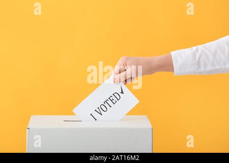 Wahlfrau in der Nähe der Wahlurne auf Farbhintergrund Stockfoto