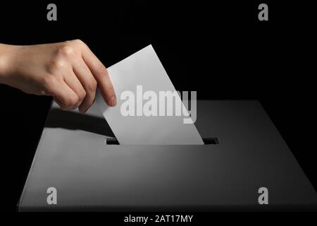 Wahlfrau in der Nähe der Wahlurne auf dunklem Hintergrund Stockfoto