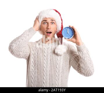 Überraschter junger Mann in Santa Hut und mit Wecker auf weißem Hintergrund. Weihnachts-Countdown-Konzept Stockfoto