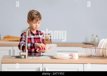 Kleiner Junge, der Geschirr in der Küche waschen kann Stockfoto