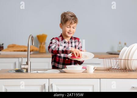 Kleiner Junge, der Geschirr in der Küche waschen kann Stockfoto