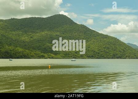 See mit ruhigem, grünem Wasser mit bewaldeten Bergen im Hintergrund am sonnigen Tag. Schöne Seenlandschaft im Süden Brasiliens - Florianopolis. Stockfoto