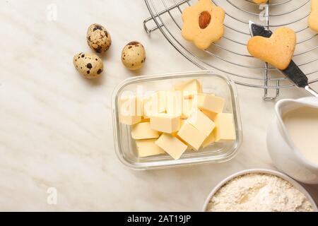 Schüssel mit frischer Butter und Zutaten für Plätzchen auf dem Tisch Stockfoto