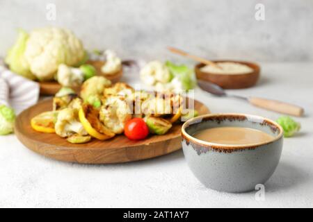 Schüssel mit schmackhaftem Tahini und gegrilltem Gemüse auf dem Tisch Stockfoto