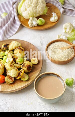 Schüssel mit schmackhaftem Tahini und gegrilltem Gemüse auf dem Tisch Stockfoto