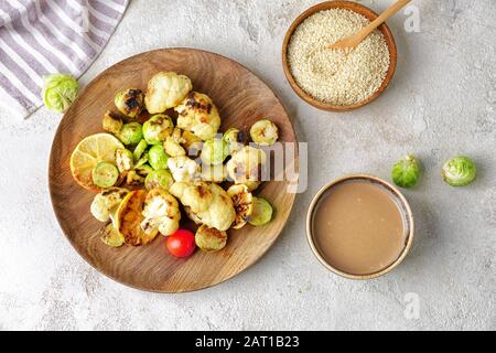 Schüssel mit schmackhaftem Tahini und gegrilltem Gemüse auf dem Tisch Stockfoto