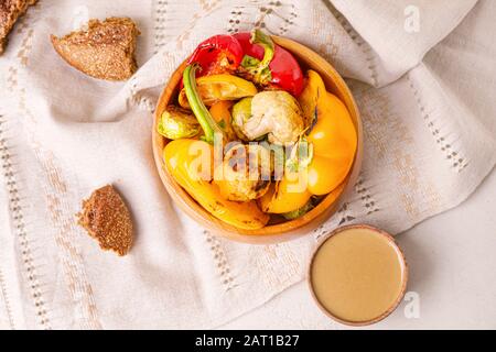 Schüssel mit gegrilltem Gemüse und leckeren Tahini auf dem Tisch Stockfoto