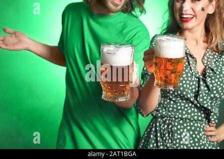 Junges Paar mit Bier auf Farbhintergrund. St. Patrick's Day Celebration Stockfoto