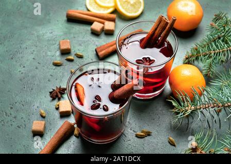 Gläser mit leckeren Glühwein und Zutaten auf Farbhintergrund Stockfoto