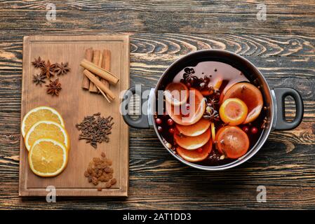 Topf mit leckerem Glühwein und Zutaten auf Holztisch Stockfoto