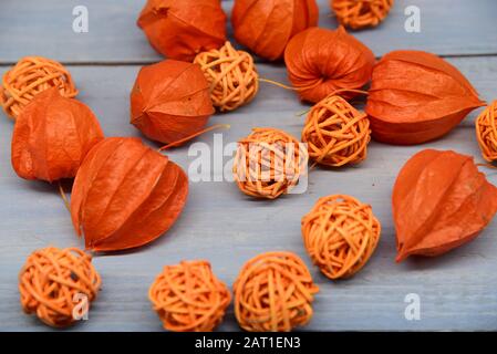 Leuchtend orangefarbene Physalis und Korbbkugeln auf blauem Holzhintergrund. Stockfoto