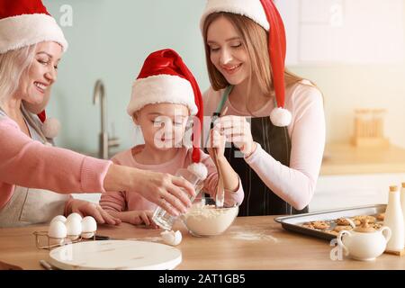 Junge Frau mit ihrer kleinen Tochter und Mutter, die zu Hause Weihnachtskekse kocht Stockfoto