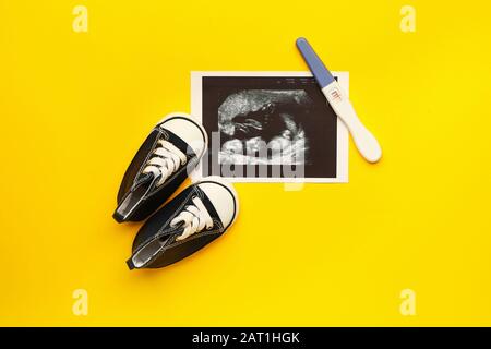 Schwangerschaftstest, Sonogrammbild und Babybooties auf Farbhintergrund Stockfoto