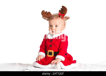 Süßes kleines Baby in Weihnachtsmanntracht und Hirschhörner auf weißem Hintergrund Stockfoto