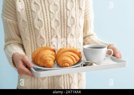 Frau, die Tablett mit leckeren Croissants und Kaffee hält, in der Nähe Stockfoto