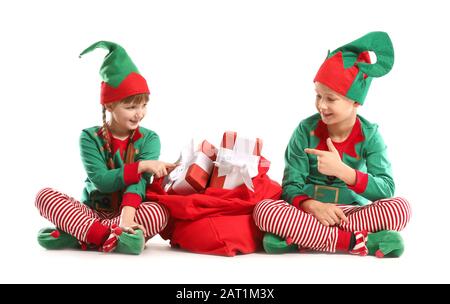 Kleine Kinder im Kostüm von Elb und mit Weihnachtsmann Tasche voller Geschenke auf weißem Hintergrund Stockfoto