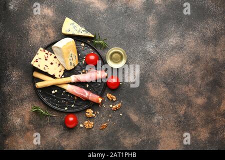 Teller mit frischem Käse, Honig und Snacks auf grauem Hintergrund Stockfoto