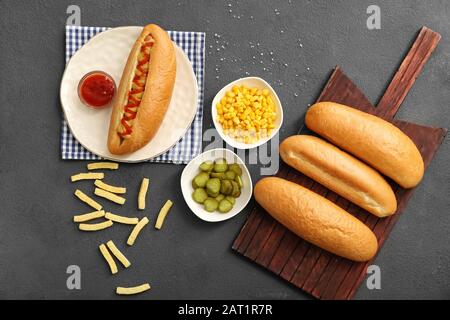 Leckerer heißer Hund und Zutaten auf grauem Hintergrund Stockfoto