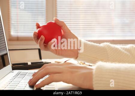 Frau drückt Stressball, während sie mit Laptop im Büro arbeitet Stockfoto