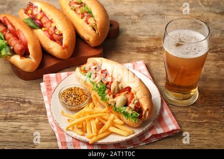 Leckere Hot Dogs mit pommes frites und Bier auf Holzgrund Stockfoto