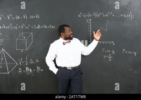 Afroamerikanischer Mathematiklehrer in der Nähe von Tafel im Klassenzimmer Stockfoto