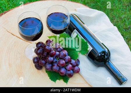 Zwei Gläser Rotwein und ein Trauben auf einem Holztisch auf grünem Gras. Draufsicht. Stockfoto