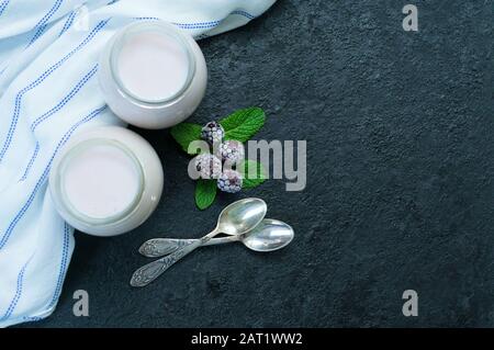 Zwei Gläser blackberry Joghurt auf schwarzem Hintergrund. Kopierbereich. Ansicht von oben. Stockfoto