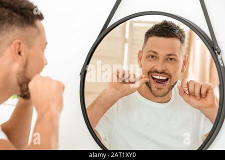 Gutaussehender Mann flossing Zähne zu Hause Stockfoto