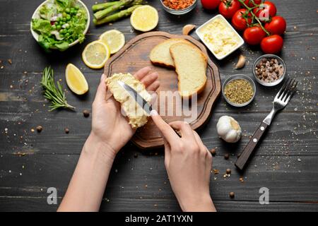 Frau, die leckere Toasts mit Frischkäse am Tisch zubereitet Stockfoto