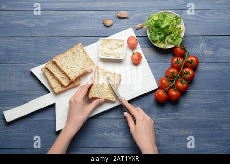 Frau, die leckere Toasts mit Frischkäse am Tisch zubereitet Stockfoto