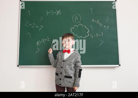 Kleiner Schuljunge in der Nähe von Tafel im Klassenzimmer Stockfoto