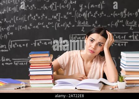 Müde Lehrerin am Tisch im Klassenzimmer Stockfoto