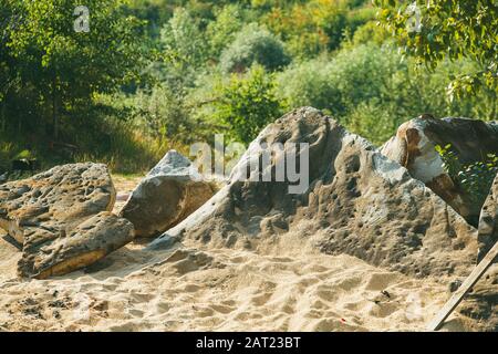 Riesige alte Kopfsteinpflaster liegen auf dem Sand auf einem Hügel mit Gras und Sträuchern überwuchert. Frühling sonniger Tag. Makroaufnahme mit selektivem Fokus und flachem Freiheitsgrad Stockfoto