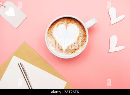 Tasse Kaffee Latte mit Herzform und Valentinen-Deko auf pinkfarbenem Hintergrund Stockfoto