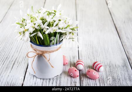 Blumenstrauß mit Schneefällen in einer Vase und ostereiern auf einem alten Holztisch Stockfoto