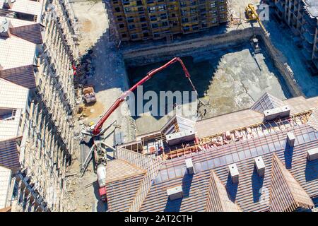 Bau einer mehrstöckigen Wohnanlage. Luftansicht. Betonfundament eines der Gebäude. Durch die Füllung wird die Betonpumpe hergestellt Stockfoto