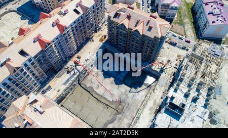 Bau einer mehrstöckigen Wohnanlage. Luftansicht. Betonfundament eines der Gebäude. Durch die Füllung wird die Betonpumpe hergestellt Stockfoto