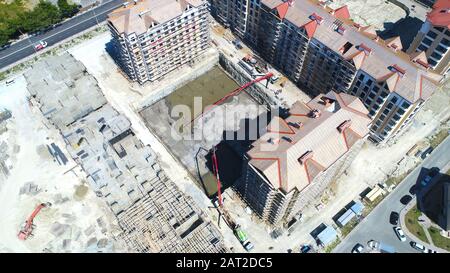 Bau einer mehrstöckigen Wohnanlage. Luftansicht. Betonfundament eines der Gebäude. Durch die Füllung wird die Betonpumpe hergestellt Stockfoto